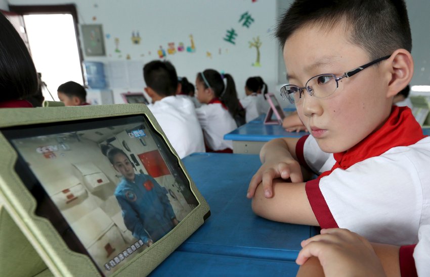 A student looks at his iPad as his class watches a live broadcast of a lecture given by Shenzhou-10 spacecraft astronauts on the Tiangong-1 space module, at a primary school in Quzhou