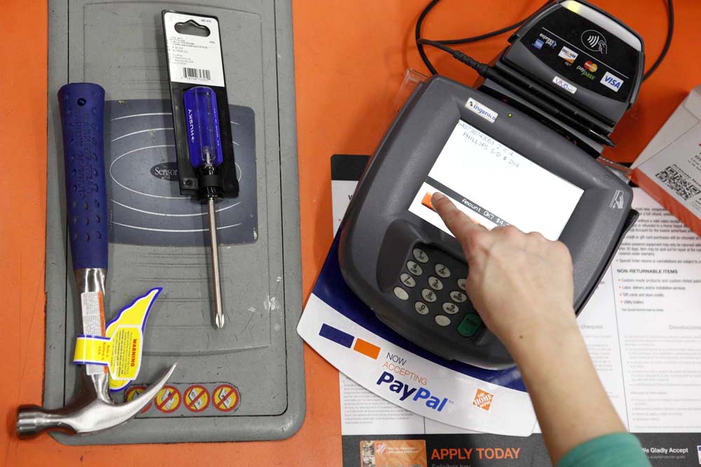 A public relations representative demonstrates how a PayPal customer can pay for goods using their mobile phone number at a cashier station at a Home Depot store in Daly City