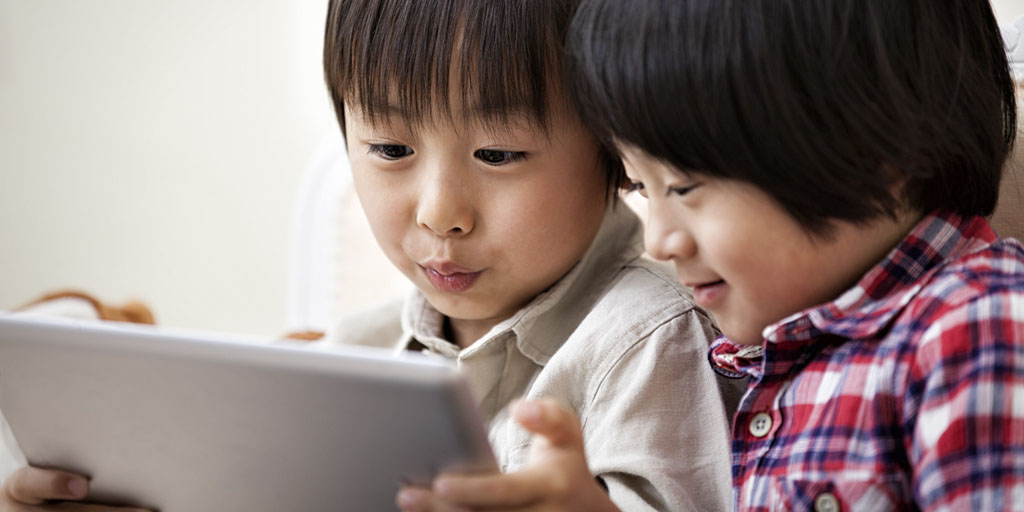 Two boys playing with a digital tablet.