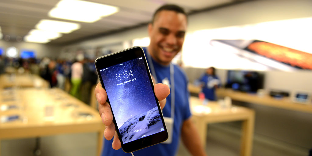IMAGE DISTRIBUTED FOR APPLE - An Apple Store employee shows off a new iPhone at the iPhone 6 launch at the Eaton Centre Apple Store on Friday, September 19, 2014, in Toronto. (Photo by Ryan Emberley/Invision for Apple/AP Images)