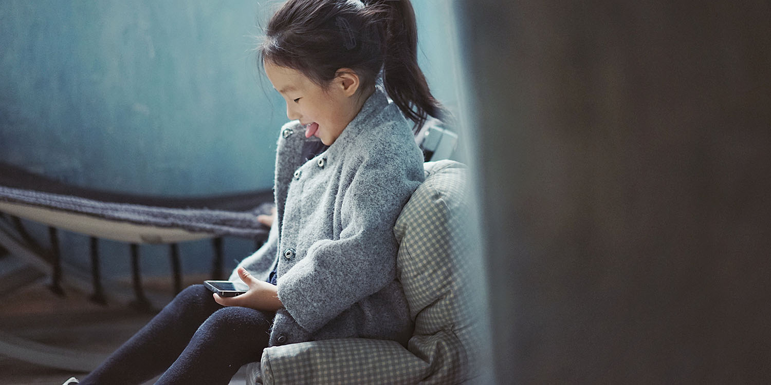 Screen Time for kids | Young girl smiling while using iPhone