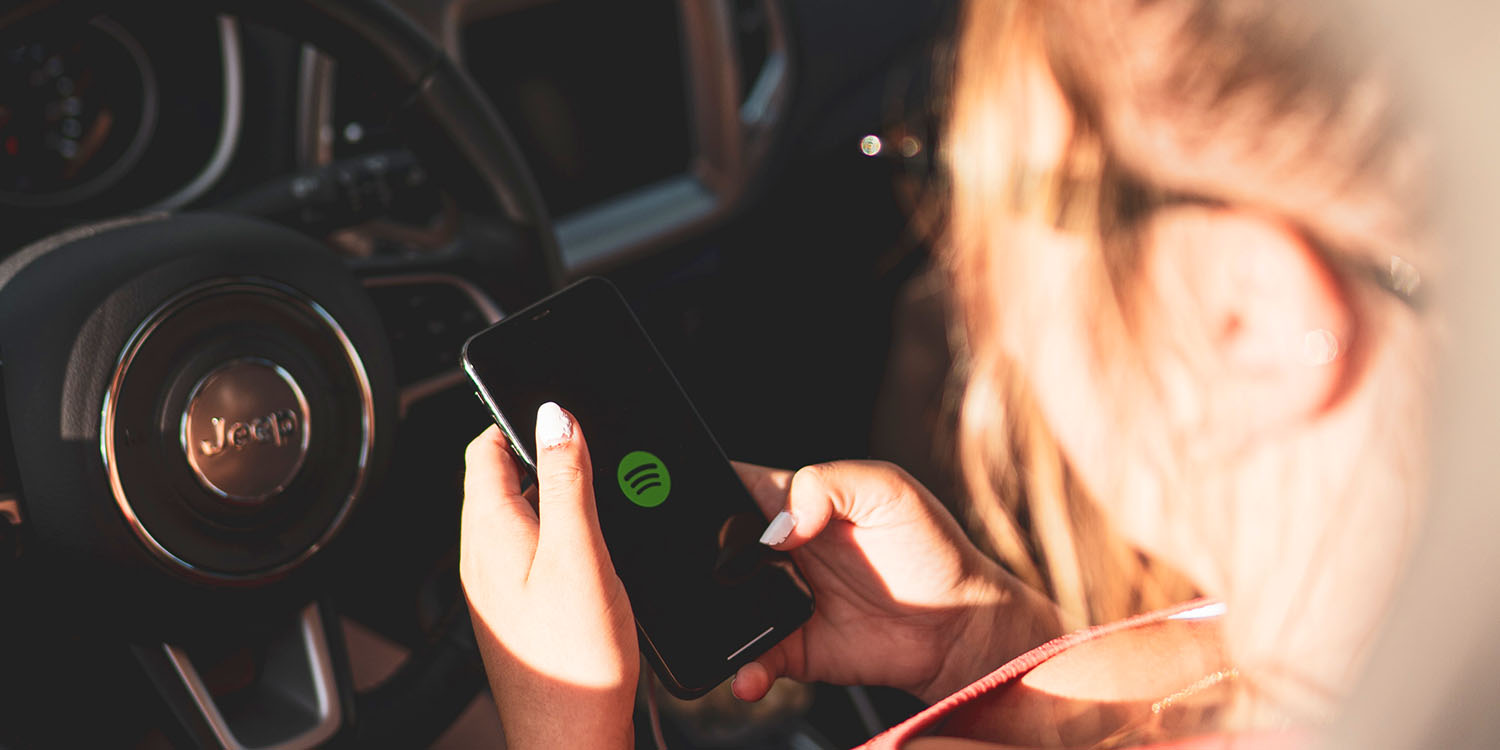 Latest Spotify layoffs | App on iPhone in a Jeep